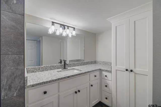 a bathroom with a granite countertop sink and a mirror