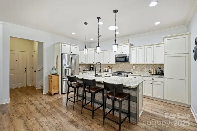 a kitchen with stainless steel appliances kitchen island granite countertop a sink and a refrigerator