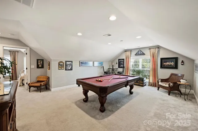 a living room with furniture pool table and glass windows
