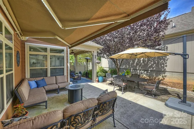 a view of a patio with a dining table and chairs under an umbrella with a barbeque