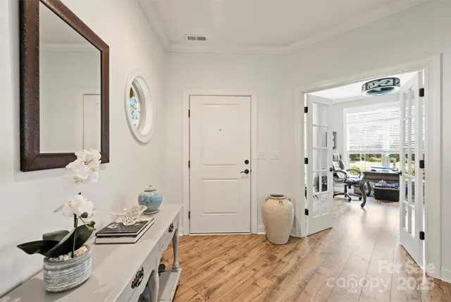 a living room with furniture and a large mirror next to a window