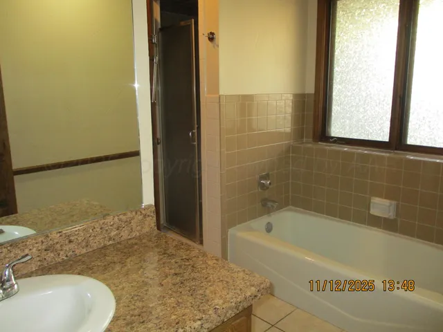 a bathroom with a granite countertop sink and a bathtub
