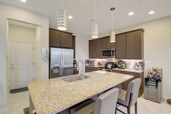 a kitchen with granite countertop a table chairs microwave and refrigerator