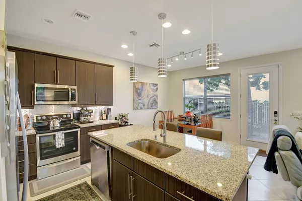 a kitchen with stainless steel appliances granite countertop a sink a stove and a refrigerator