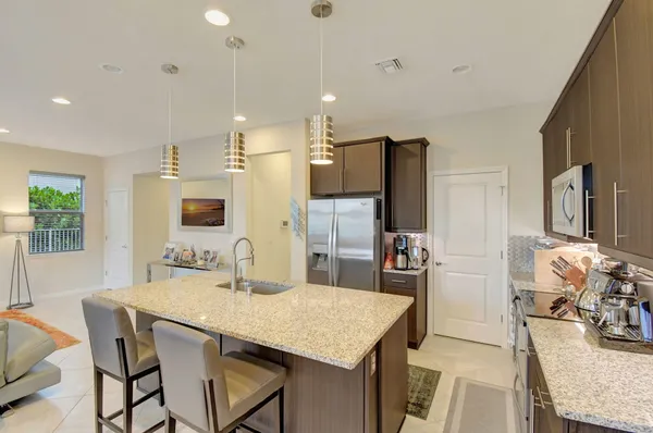 a kitchen with stainless steel appliances kitchen island granite countertop a kitchen island and a refrigerator