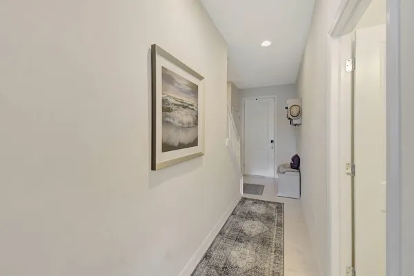 a view of a hallway with wooden floor and a bathroom