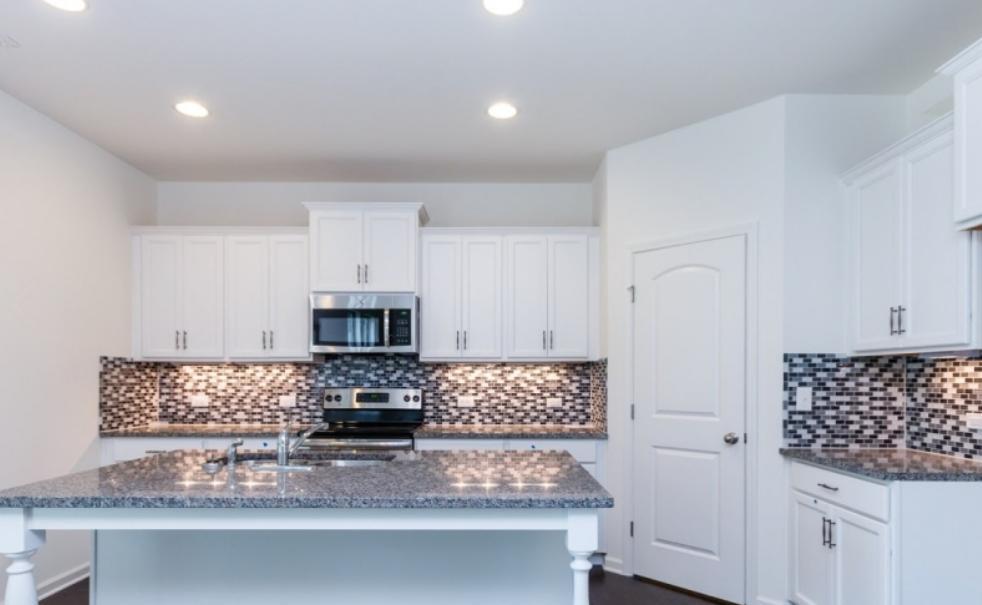 a kitchen with granite countertop a stove a microwave a sink and cabinets