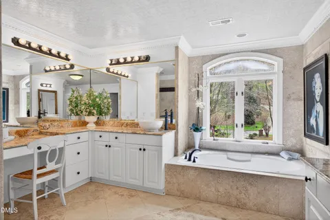 a bathroom with a bathtub a sink a mirror a vanity a window and a shower