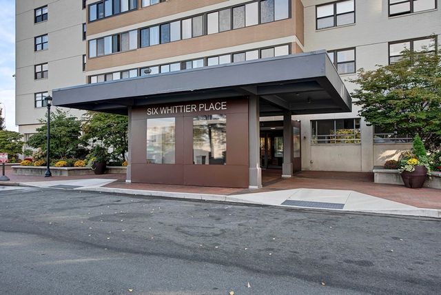 a front view of a building with a garden and parking garage