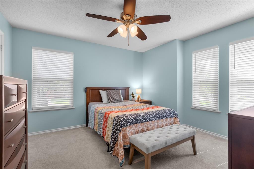 410 Simmons Road Double Oak, TX 75077 - Photo 26 of 40 Bright bedroom with ceiling fan and cozy carpet.