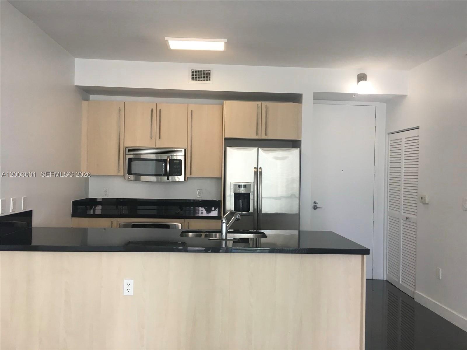 1111 Southwest 1st Avenue, Unit 2223N Miami, FL 33130 - Photo 9 of 39 a kitchen with stainless steel appliances granite countertop a sink and a refrigerator