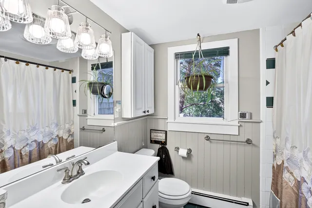 a bathroom with a sink a mirror a window and a shower