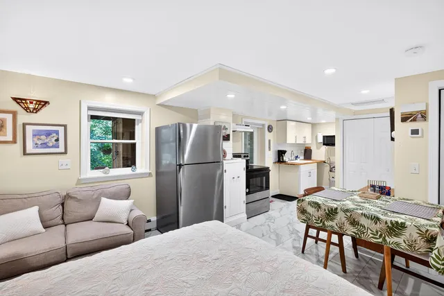 a living room with kitchen island stainless steel appliances furniture a refrigerator a sink a counter top space and living room view