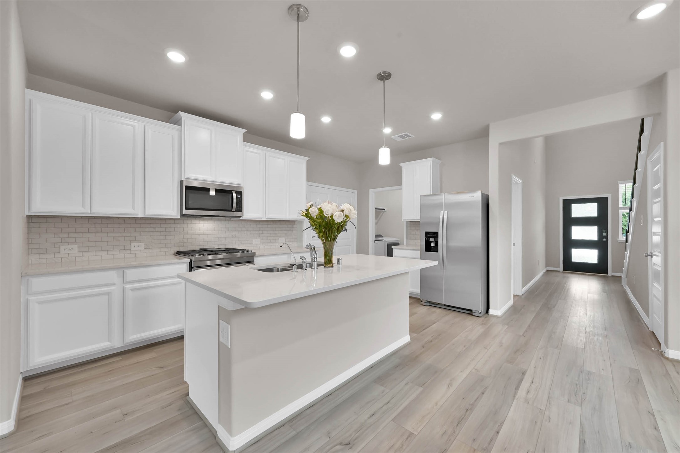 213 Harper Ridge Drive Montgomery, TX 77316 - Photo 7 of 34 a kitchen with stainless steel appliances kitchen island granite countertop a stove a refrigerator a sink dishwasher and a microwave with wooden floor