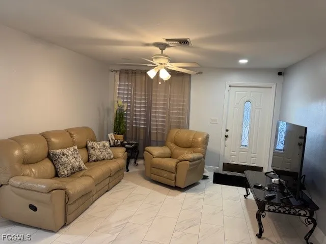 a living room with furniture a ceiling fan and a window