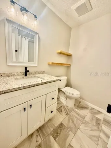 a bathroom with a granite countertop sink a toilet and a mirror
