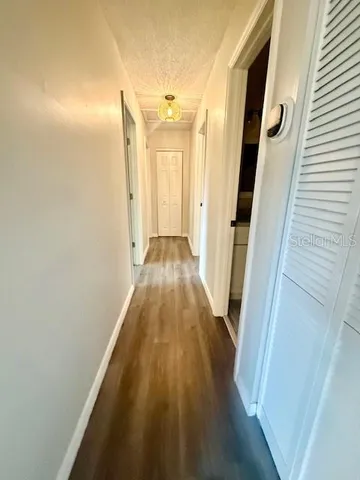 a view of a hallway with wooden floor and cabinet