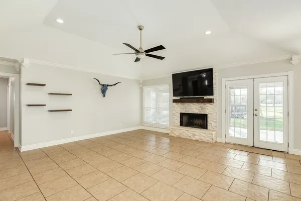 a view of a livingroom with a fireplace a ceiling fan and windows