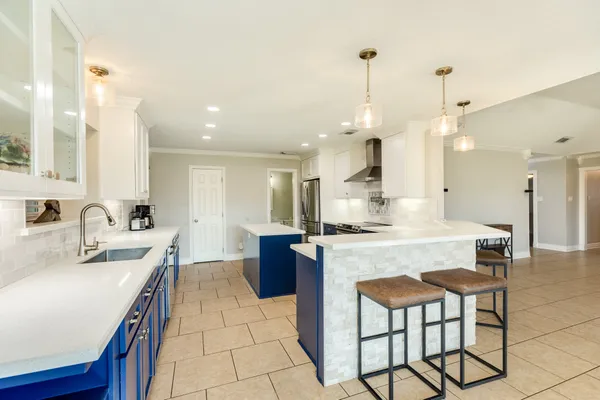 a kitchen with a stove a sink a kitchen island with a dining table and chairs