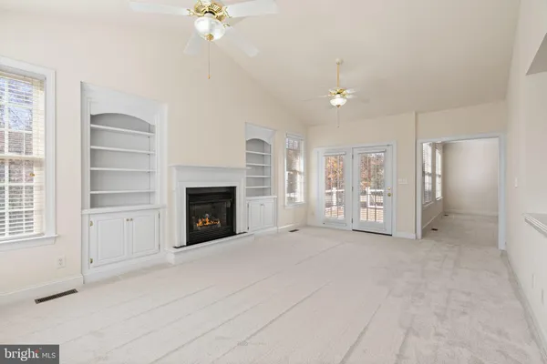 an empty room with windows and fireplace