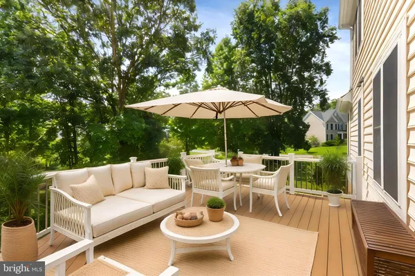 a view of a patio with couches table and chairs under an umbrella with a garden