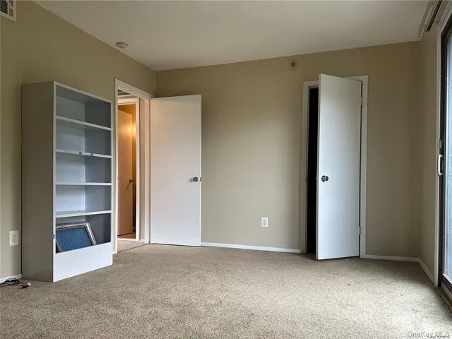 a view of an empty room with wooden floor and a cabinet