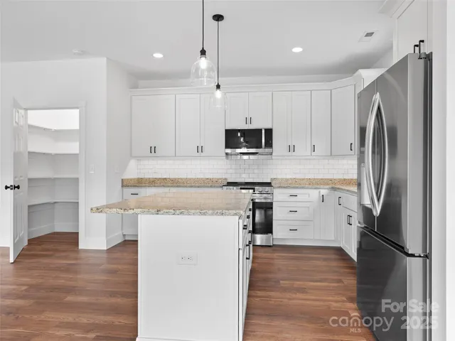 a large kitchen with granite countertop a large stove a sink and a wooden floor