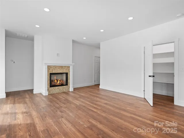 a view of an empty room with wooden floor fireplace and a window