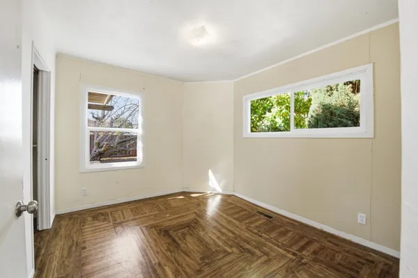 a view of empty room with wooden floor and fan