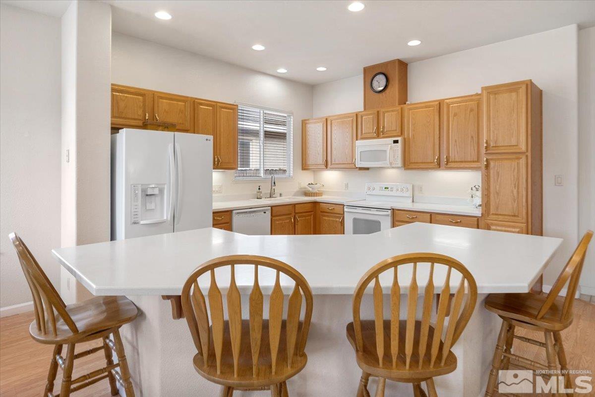 10055 Kentfield Place Reno, NV 89521 - Photo 11 of 39 a kitchen with stainless steel appliances granite countertop a dining table chairs and a refrigerator