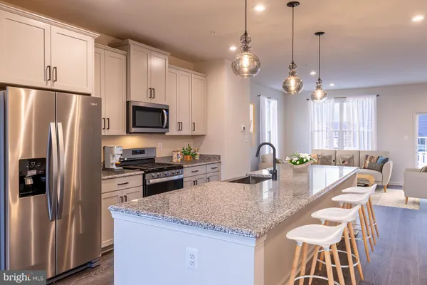 a kitchen with stainless steel appliances granite countertop a refrigerator a stove a sink a dining table and chairs