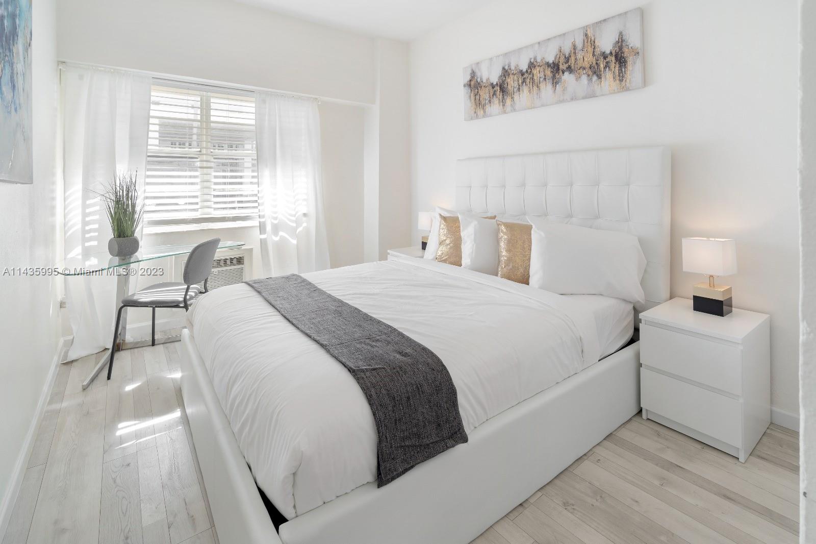 a bedroom with a white bed and white walls with wooden floor