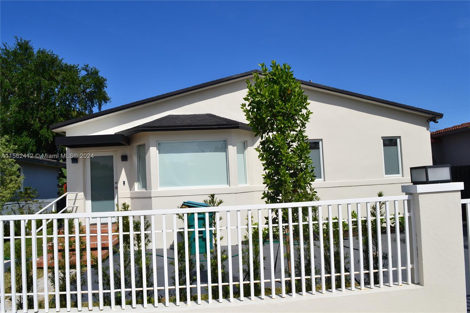 a front view of a house with white fence