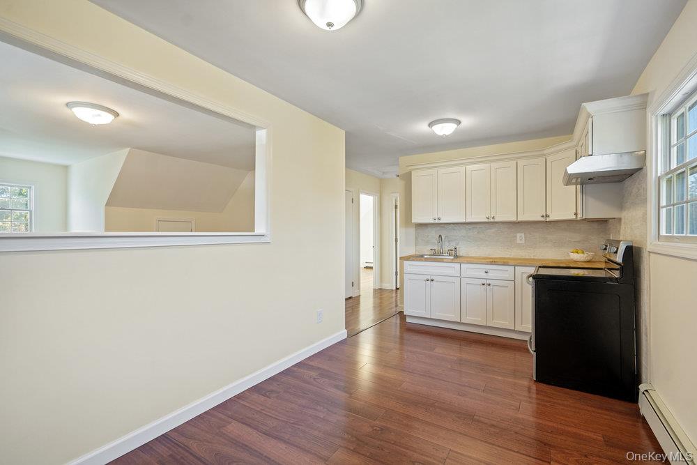 91 15th Avenue West Babylon, NY 11704 - Photo 19 of 33 a kitchen with wooden floors and white appliances