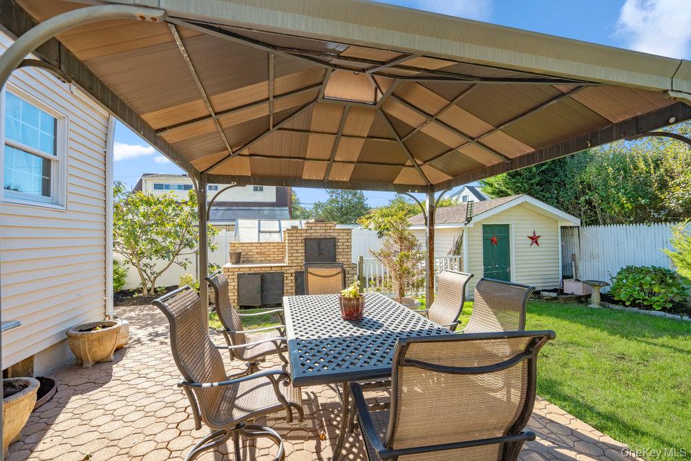 91 15th Avenue West Babylon, NY 11704 - Photo 30 of 33 a view of a patio with table and chairs under an umbrella