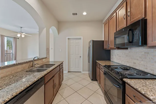 a kitchen with stainless steel appliances granite countertop a sink stove and refrigerator
