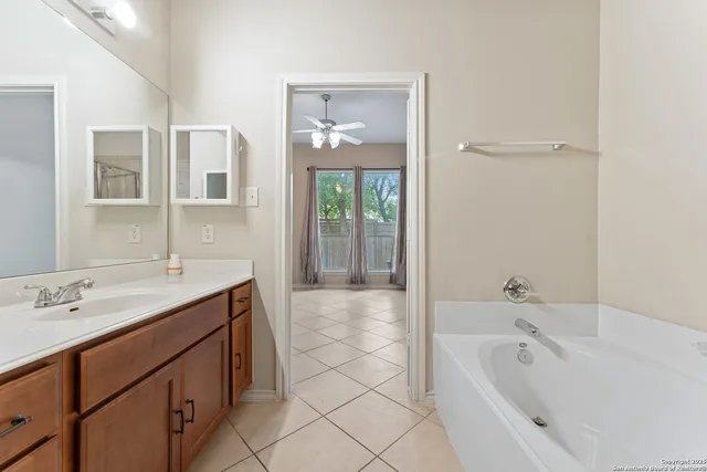 a spacious bathroom with a tub a double vanity sink a window and mirror