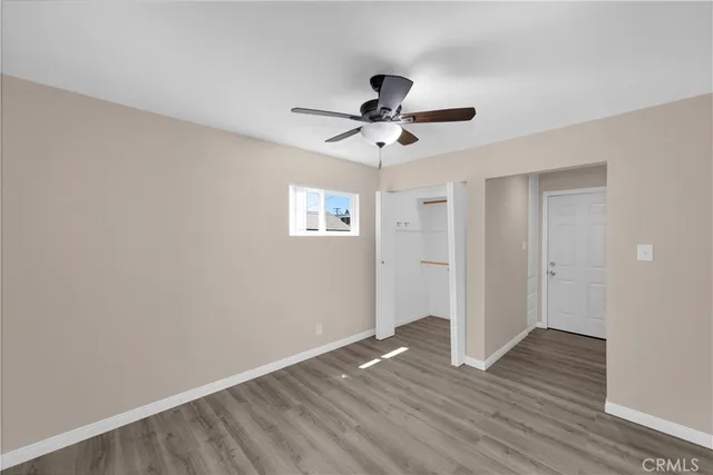 an empty room with wooden floor and a ceiling fan