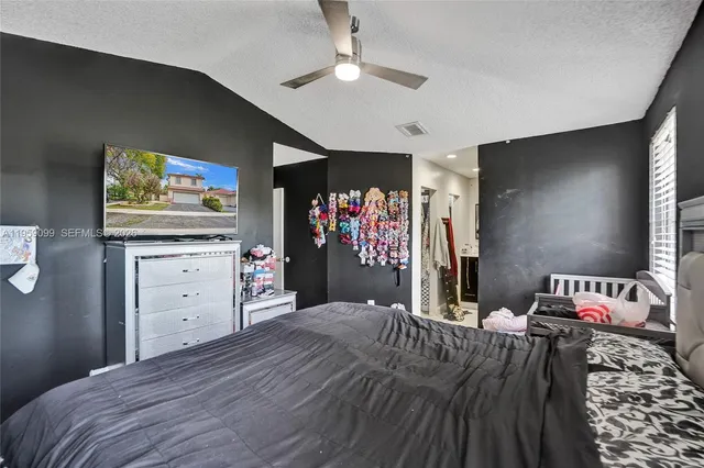 a bedroom with a bed and a flat tv screen on dresser