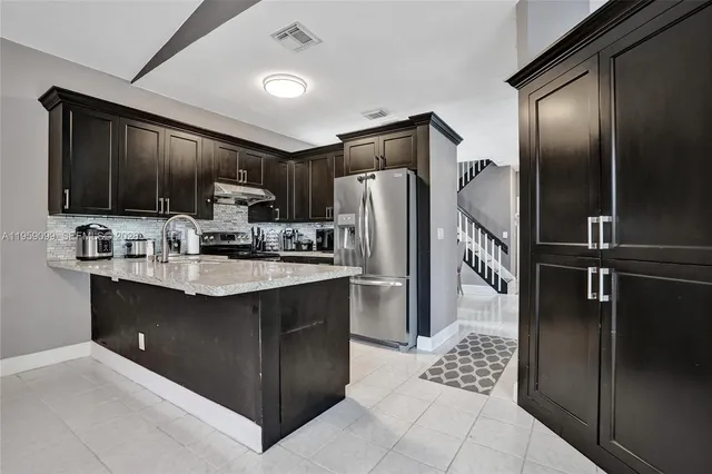 a kitchen with kitchen island granite countertop a refrigerator and a sink