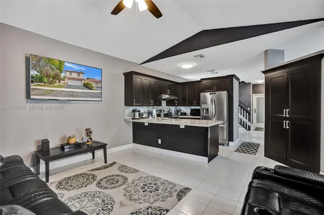 a living room with stainless steel appliances kitchen island granite countertop furniture and a rug