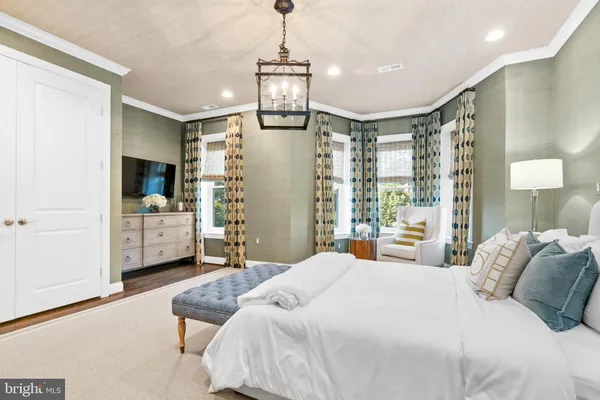 a bedroom with a bed chandelier and dresser