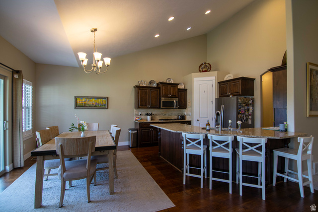646 East 1400th Street North Mapleton, UT 84664 - Photo 17 of 78 Open-concept kitchen and dining area featuring vaulted ceilings, recessed lighting, wood-finish flooring, a kitchen island with bar seating, and a sliding glass door