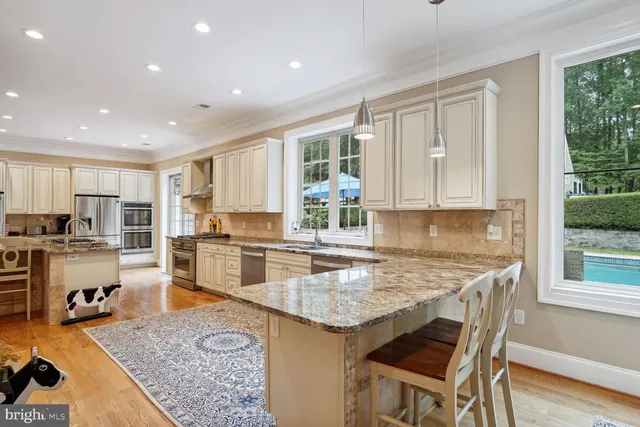 a living room with stainless steel appliances furniture a fireplace and a open kitchen view