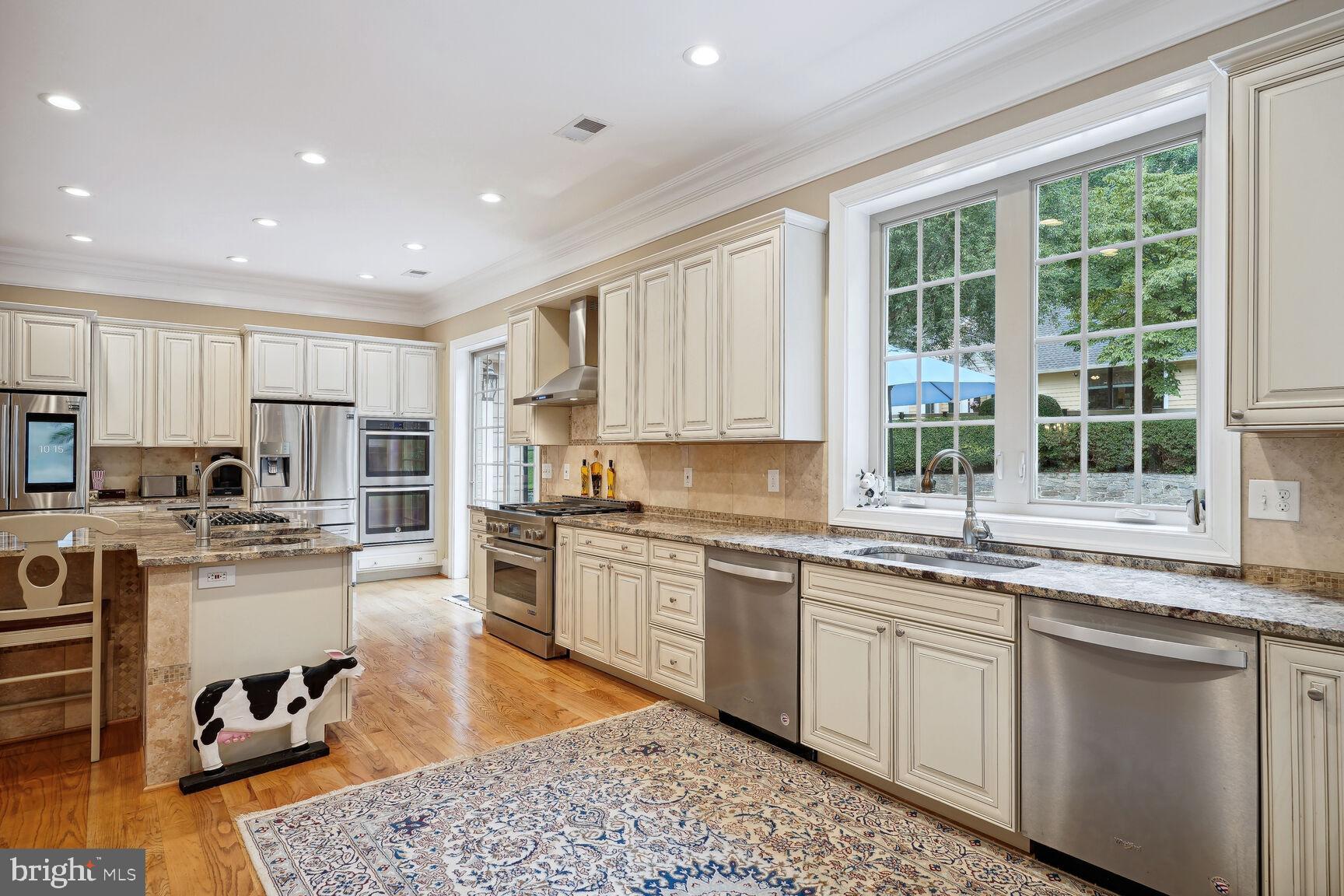10813 Lockland Road Potomac, MD 20854 - Photo 24 of 73 a kitchen with stainless steel appliances granite countertop wooden cabinets a sink dishwasher a stove and a refrigerator with wooden floor