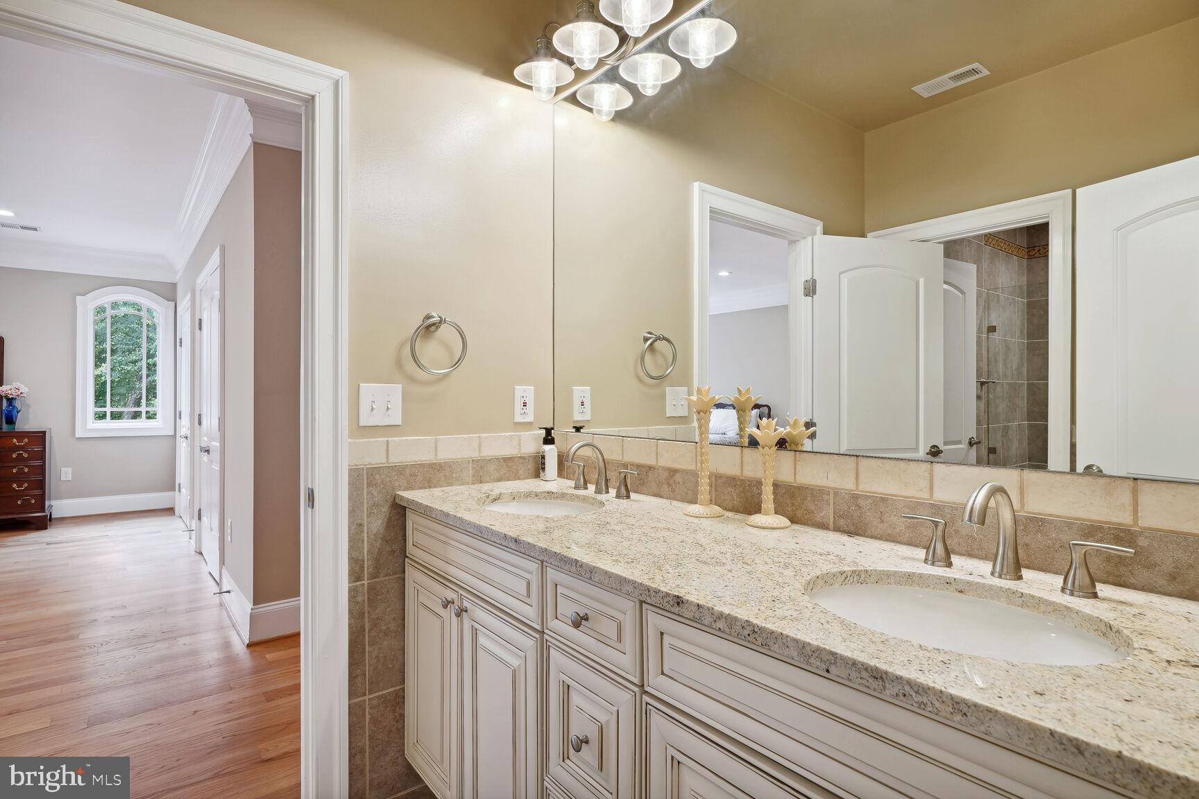 10813 Lockland Road Potomac, MD 20854 - Photo 47 of 73 a bathroom with double vanity sinks a vanity a lamp and a mirror
