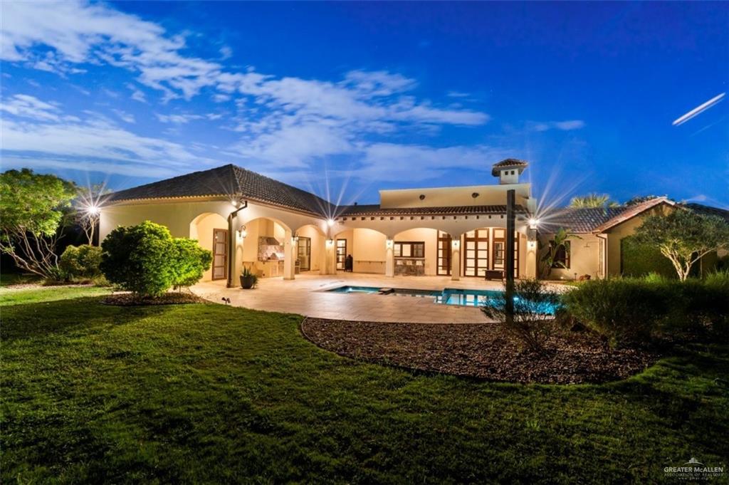 1425 Encanto Road, Unit SERVICE Weslaco, TX 78596 - Photo 11 of 45 Back of property at dusk featuring a patio area, stucco siding, a yard, and french doors