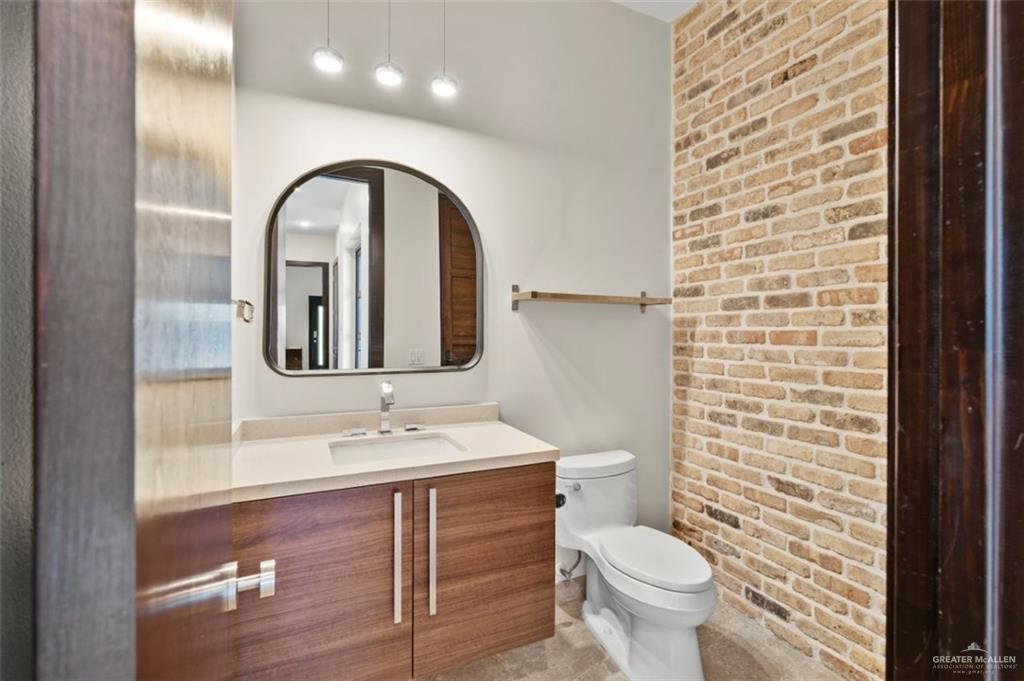 1425 Encanto Road, Unit SERVICE Weslaco, TX 78596 - Photo 35 of 45 Half bathroom with brick wall and vanity
