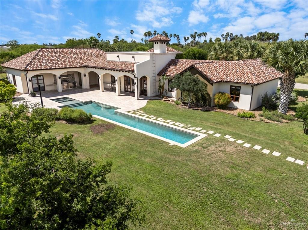 1425 Encanto Road, Unit SERVICE Weslaco, TX 78596 - Photo 5 of 45 Back of house with an outdoor pool, a patio area, stucco siding, a lawn, and a chimney