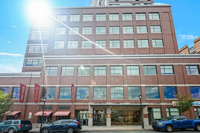 a front view of a building with a lot of cars and trees